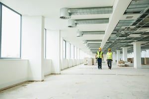 Two architects walking through a vacant office space being renovated