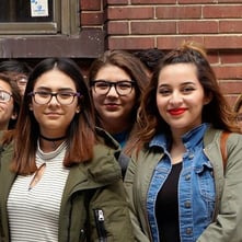 A group of young women are posing for a picture in front of a brick wall .