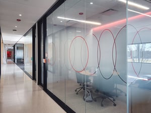 Privacy glass with a centered gradient and decorative circles partially blocks view into conference rooms at UL solutions