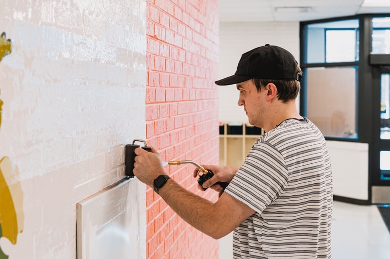 Carefully smoothing the vinyl with a roller, the installer eliminates air bubbles and secures the wall graphic for a flawless, professional finish.